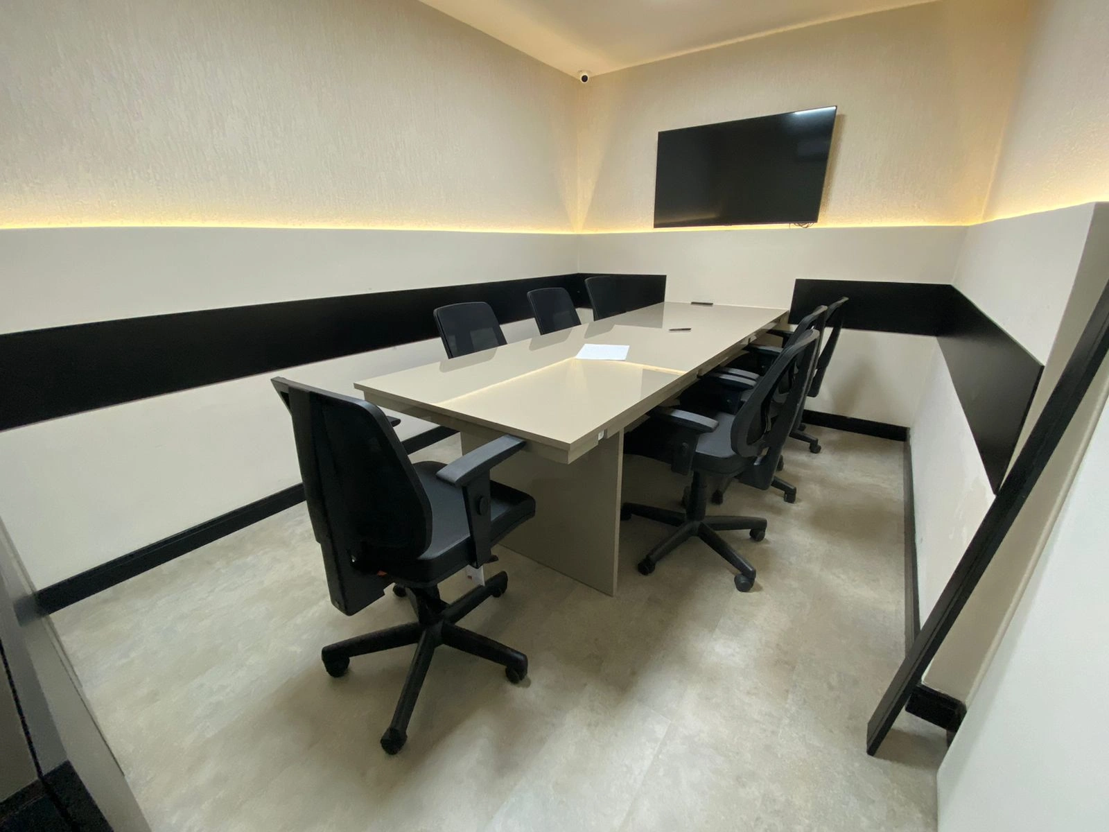 Auditório compacto com fileiras de cadeiras operacionais e painel ripado ao fundo.